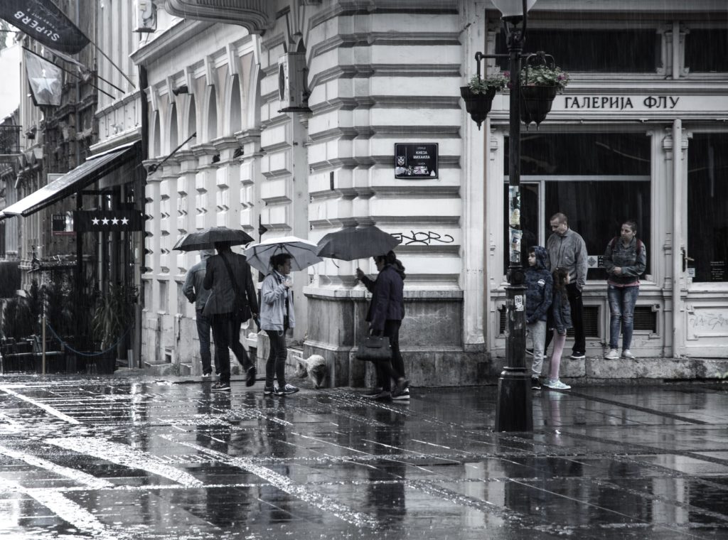 People with umbrellas standing in Knez Mihailova street in Belgrade and talking
